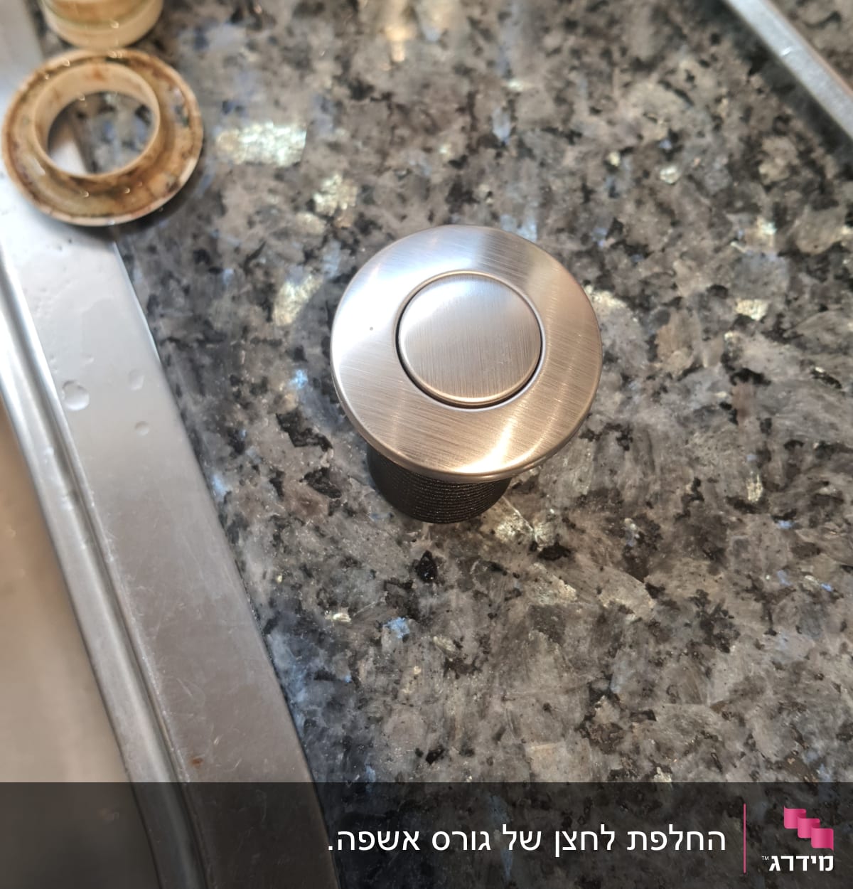 כפתור מתכת עגול על משטח שיש ליד כיור